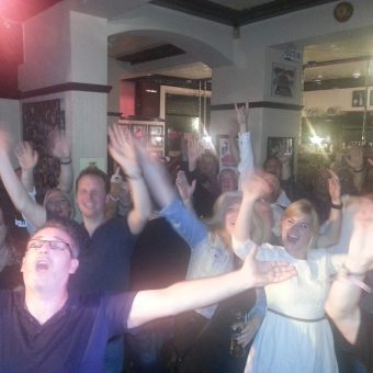 The crowd at the Pub, Lancaster, cheering and waving their arms.